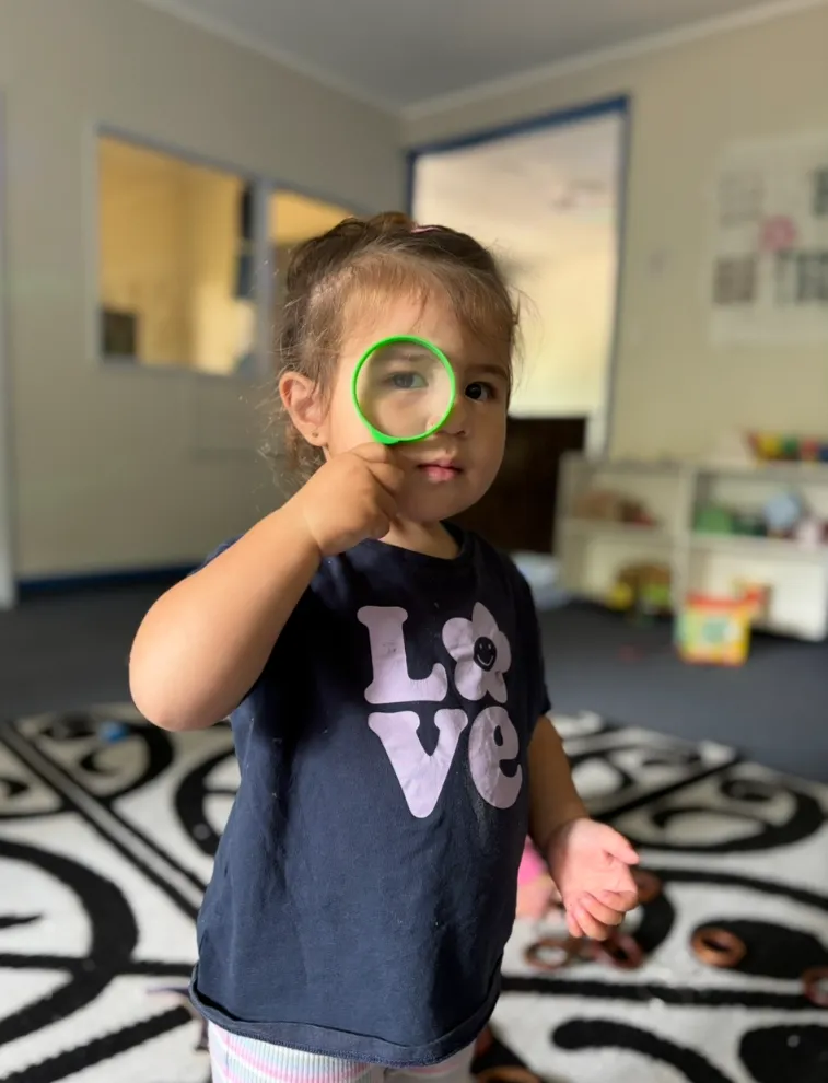 A child inspecting a treasure through a magnifying glass