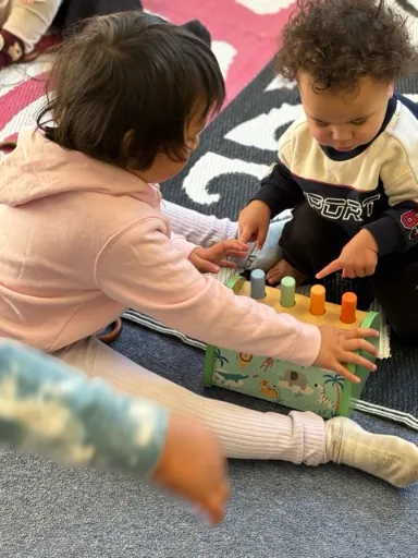 A child threading pegs into a board at the table