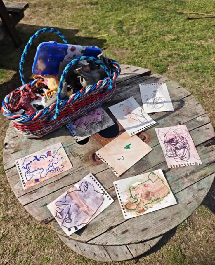 Tamariki artwork laid out to dry on the cable spool table in the sunshine