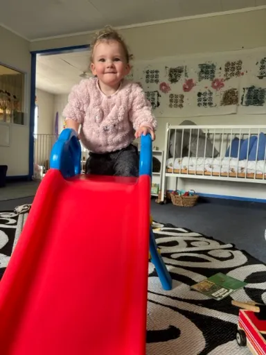 A toddler climbing the little indoor slide in the nursery