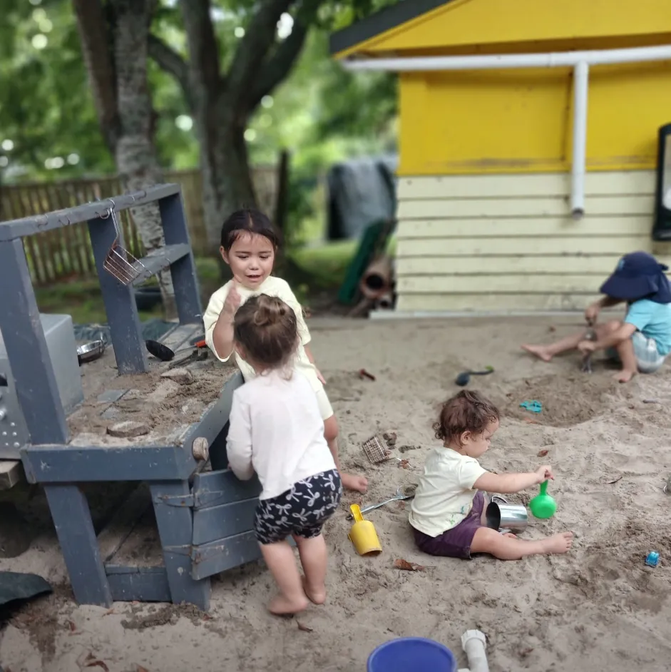 Tamariki playing together in the big sandpit and mud kitchen