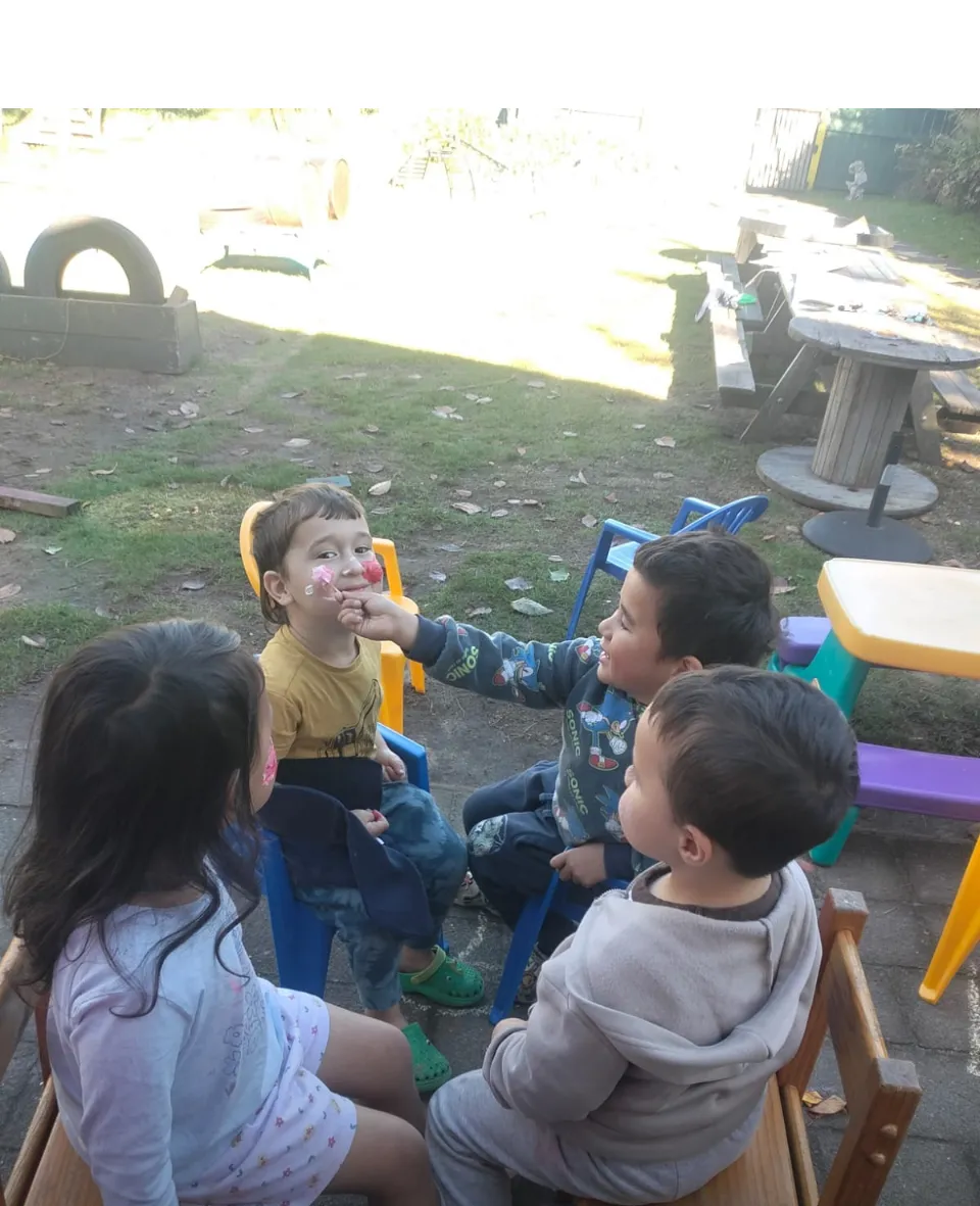 Tamariki sitting together outside doing face painting with their friends